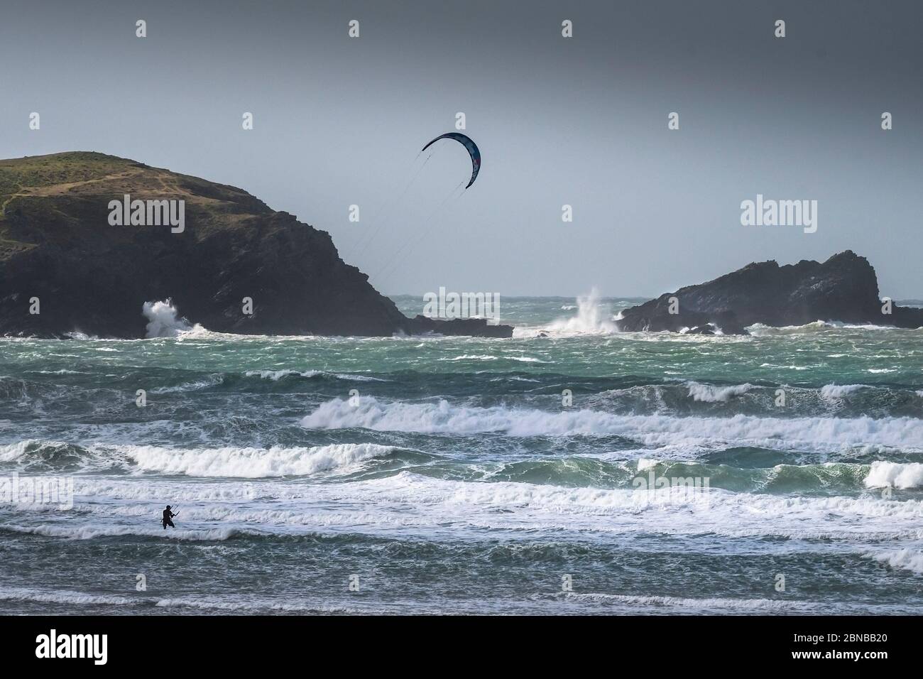 Un surfeur de kite solitaire bravant les conditions venteuses sauvages à Fistral, à Newquay, en Cornwall. Banque D'Images