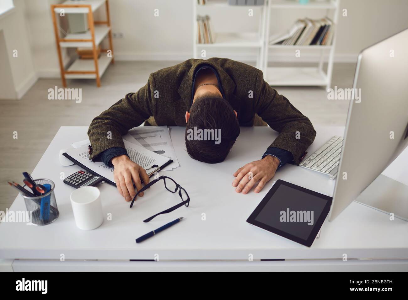 Homme d'affaires dans une veste fatigué épuisé avec des problèmes de stress couché sur le lieu de travail dans le bureau. Banque D'Images