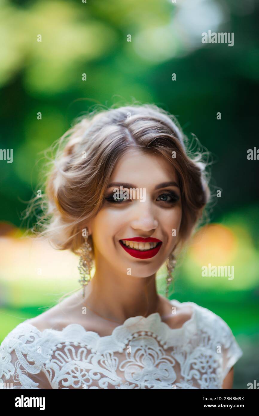 brunette mariée dans une robe avec un bouquet de mariage dans le parc sur un fond de verdure Banque D'Images