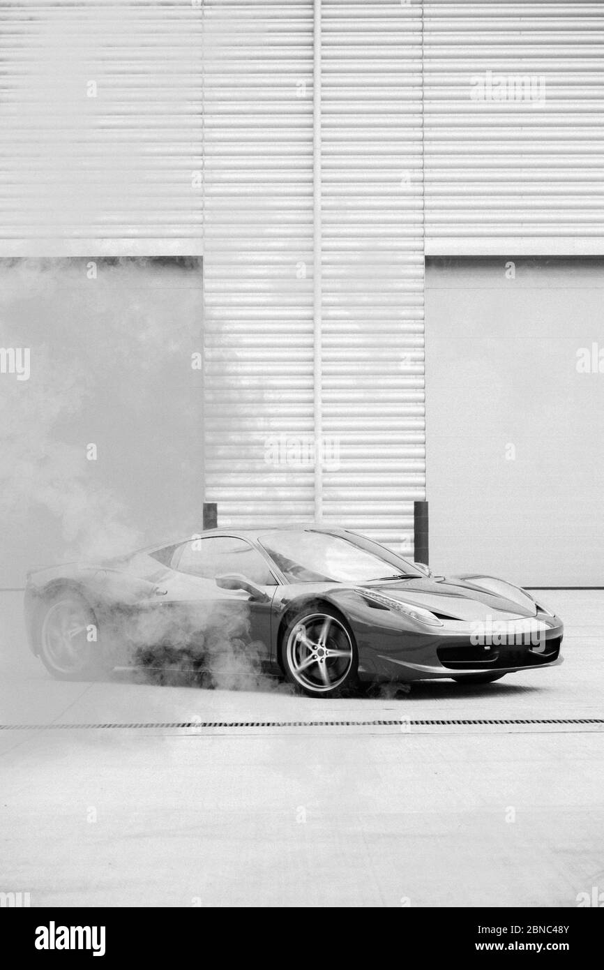 LONDRES, ROYAUME-UNI - 12 mars 2017: Photographie en noir et blanc de aFerrari 458 Italia tournant dans un parc de stationnement industriel avec fumée à venir Banque D'Images