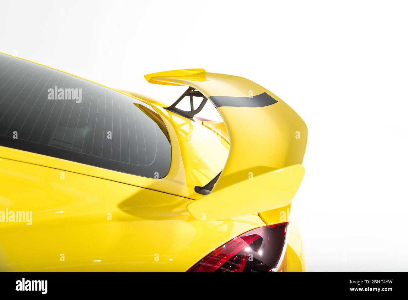 Gros plan d'un aileron sur une voiture de sport moderne jaune sous les lumières isolées sur un fond gris Banque D'Images