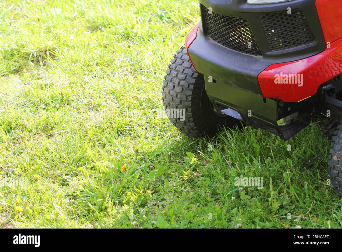 Jardinier conduisant une tondeuse à gazon dans un jardin . Coupe de l'herbe Banque D'Images