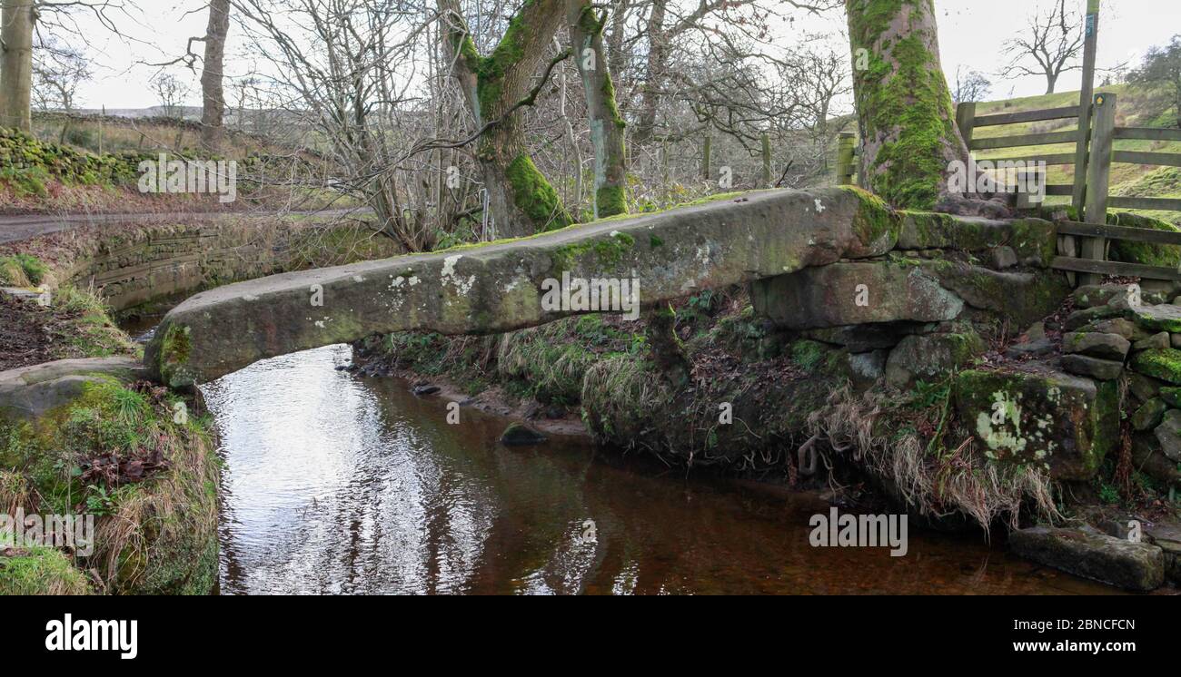 Clam Bridge, une ancienne passerelle en pierre sur Wycoller Beck dans le parc national de Wycoller. Pendle, Lancashire Banque D'Images