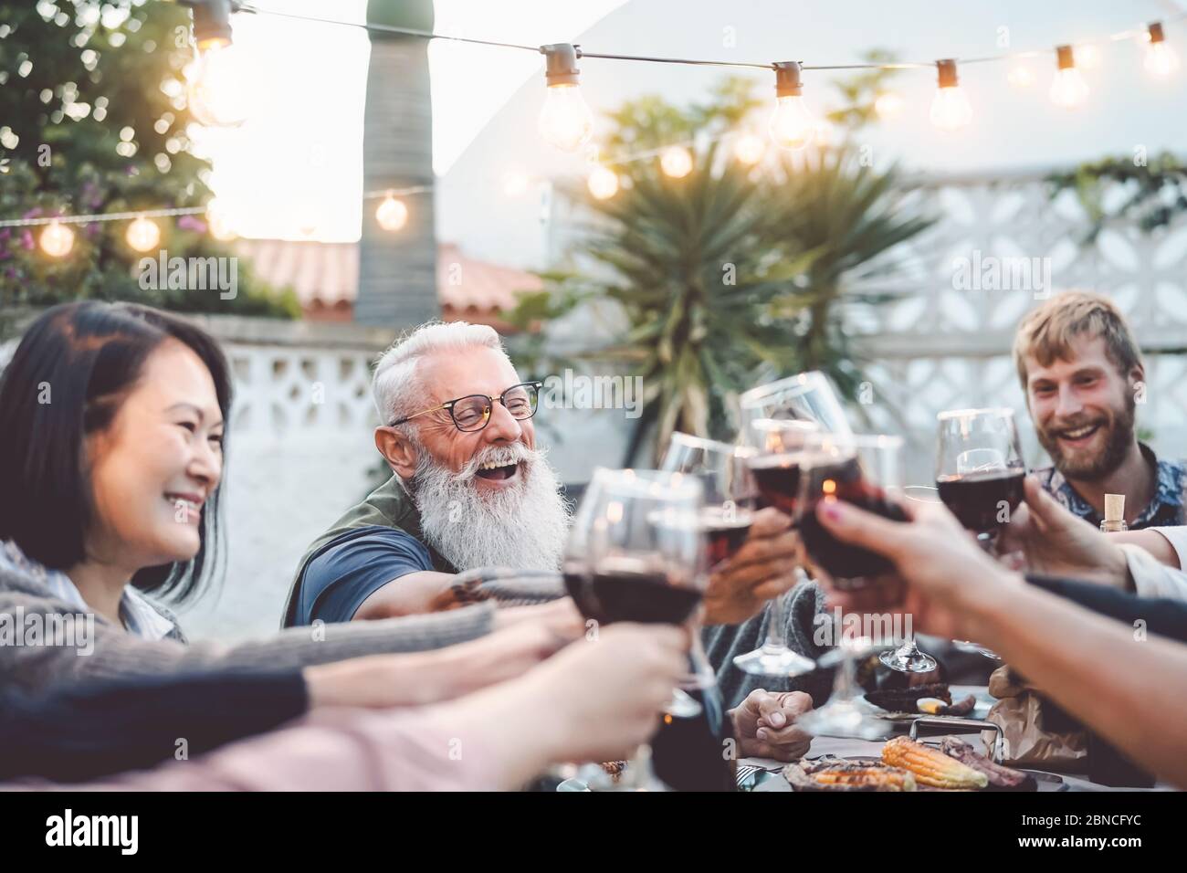 Happy Family dînant et toaster les verres à vin rouge en plein air - les personnes de différents âges et de différentes origines s'amusent dans un dîner barbecue Banque D'Images