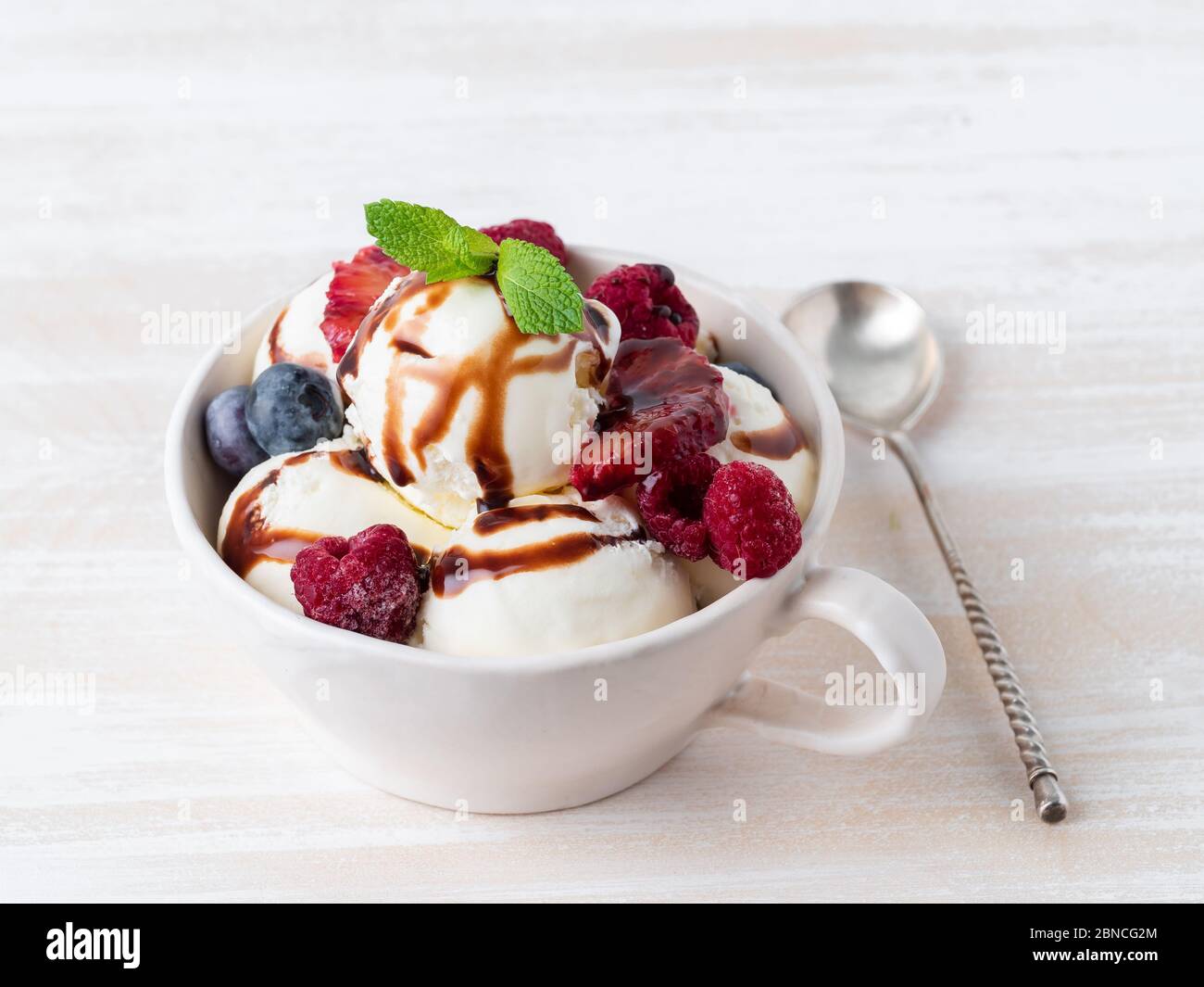 Boules de glace vanille dans un mug avec framboises et bleuets Banque D'Images