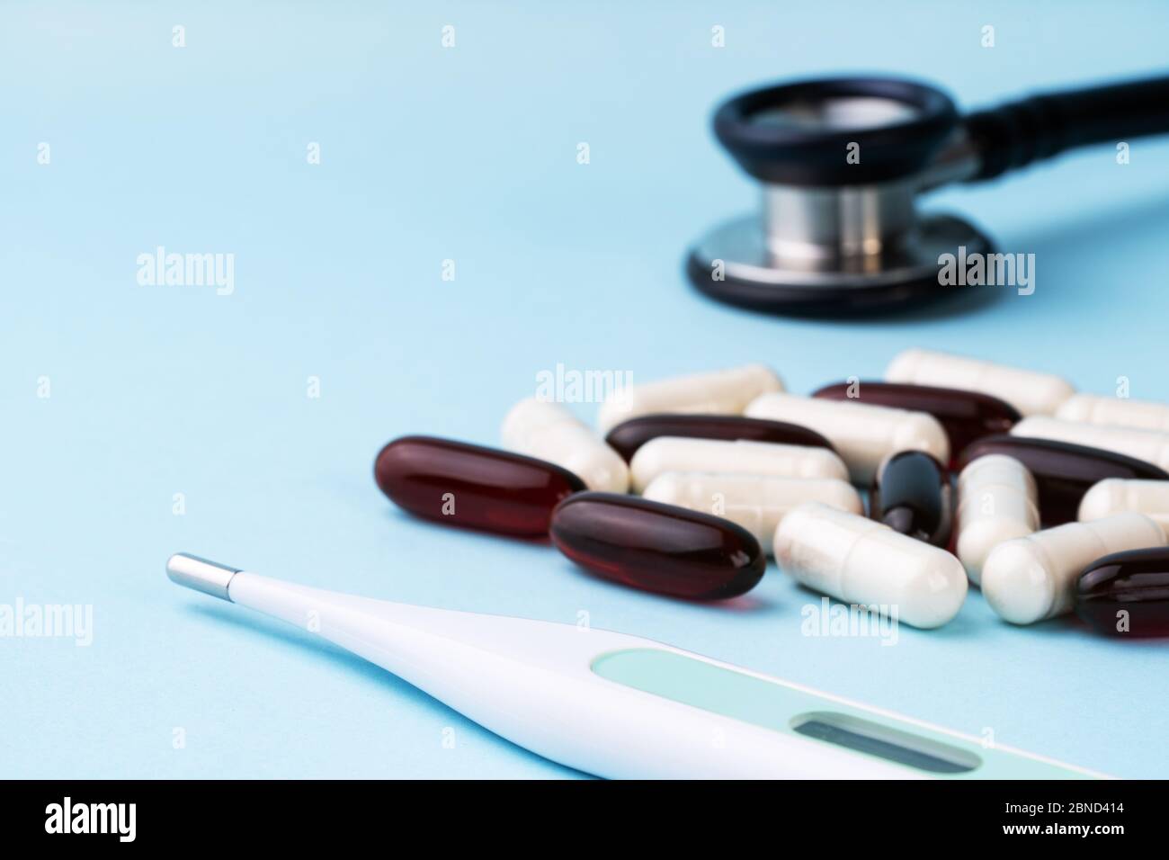 Stéthoscope, thermomètre, pilules, capsules sur bleu. Santé, assurance maladie, concept de médecine. Espace de travail du médecin. Pandémie de coronavirus Covid-19 Banque D'Images