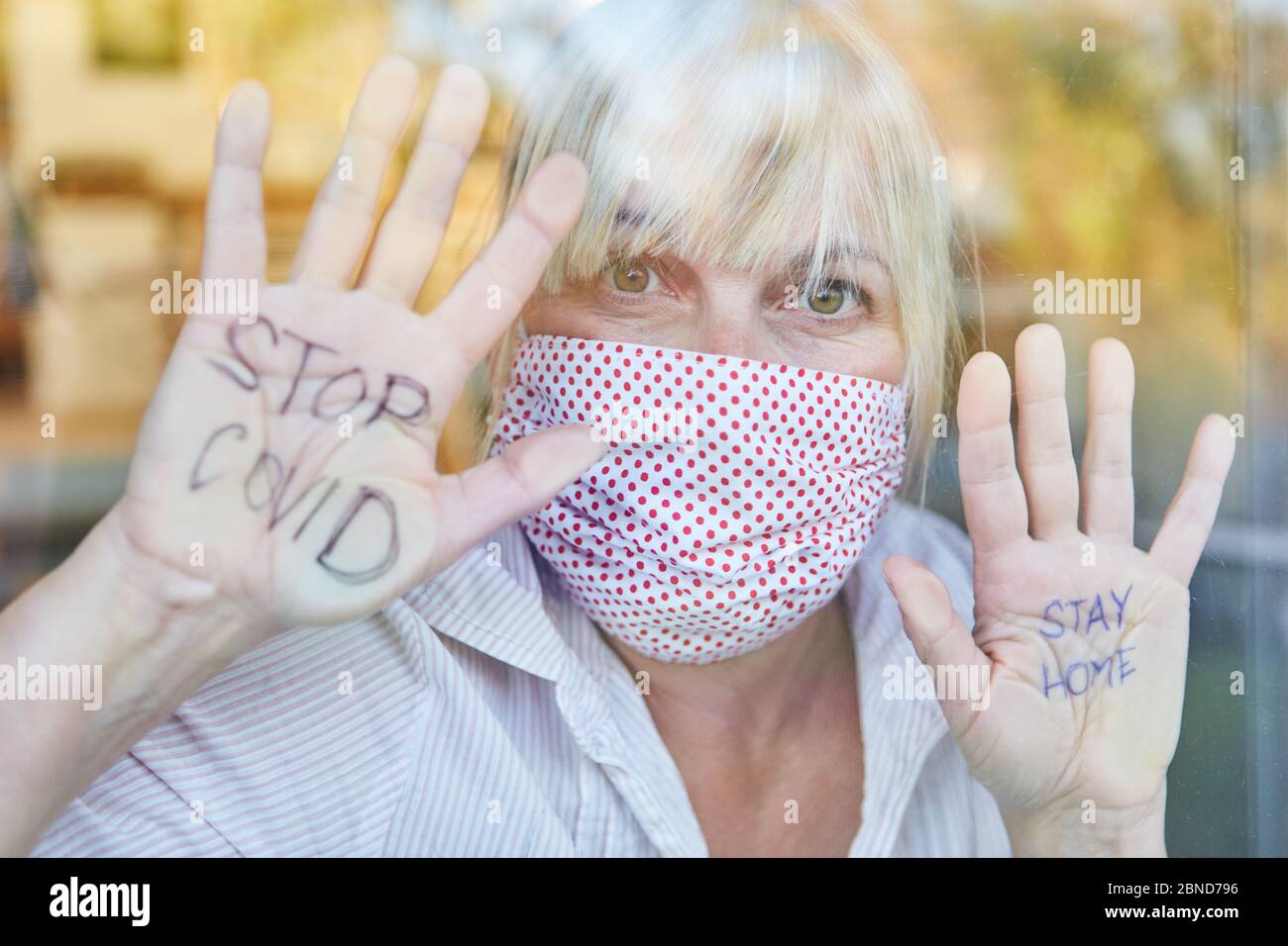 Restez à la maison et arrêtez les messages Covid sur les paumes de la femme âgée avec un protecteur de quarantaine en cas de pandémie du coronavirus Banque D'Images