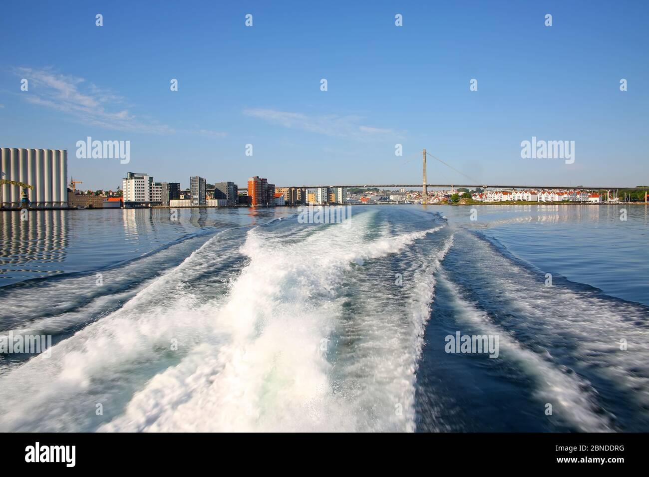 Vagues dans l'océan depuis le sillage d'un bateau. Port de Stavanger, pont de la ville et port en arrière-plan, Stavanger, comté de Rogaland, Norvège. Banque D'Images