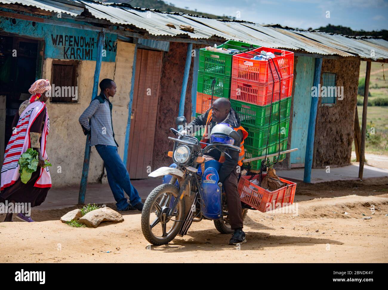 La vie dans la petite ville de Dol Dol, Kenya et l'homme livrant de la nourriture sur le motocycle Banque D'Images