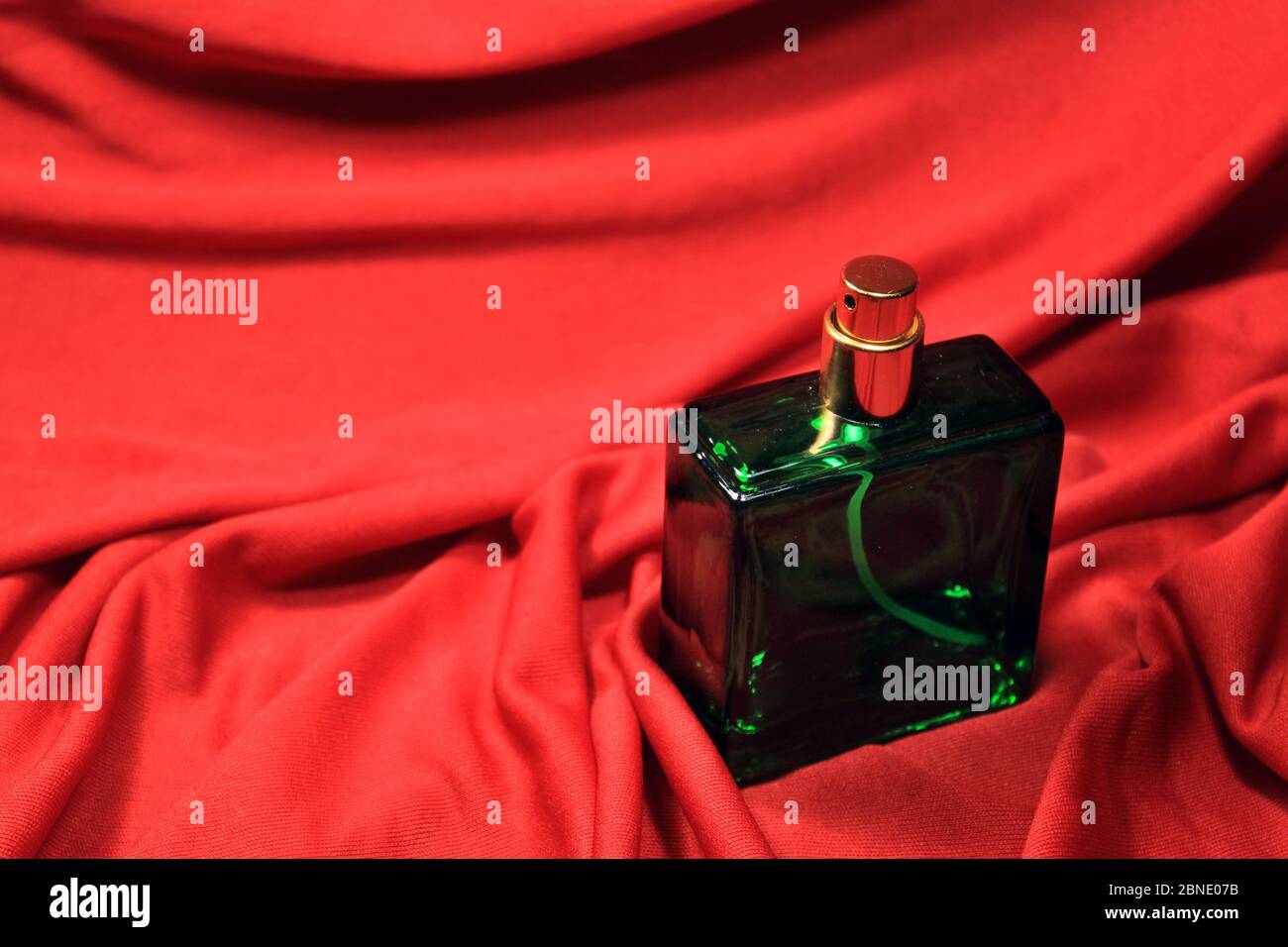 Flacon de parfum de couleur verte avec accessoires femelles isolés sur fond rouge. Banque D'Images