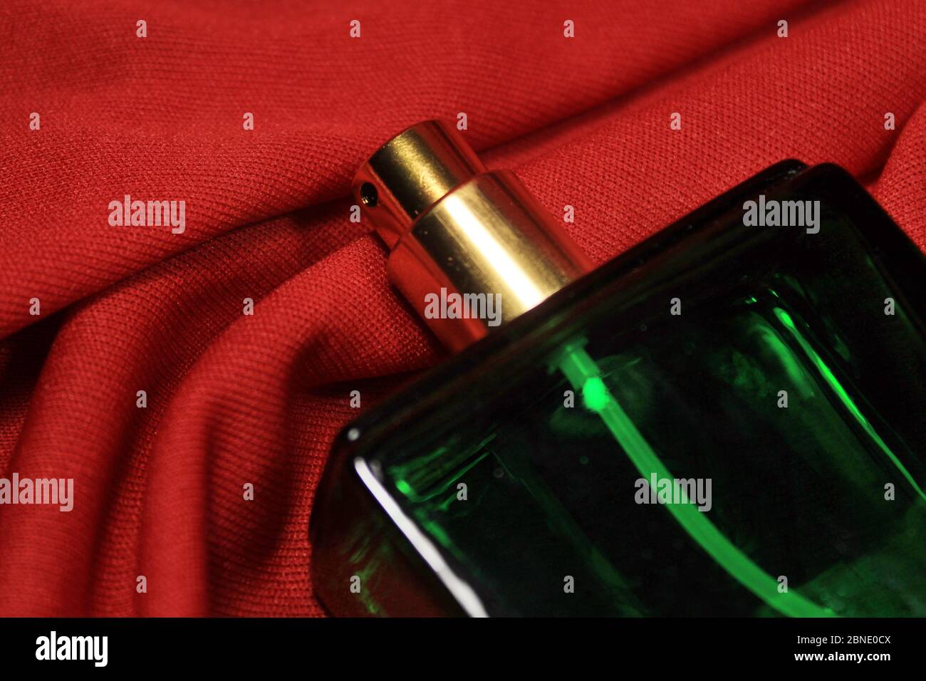 Flacon de parfum de couleur verte avec accessoires femelles isolés sur fond rouge. Banque D'Images