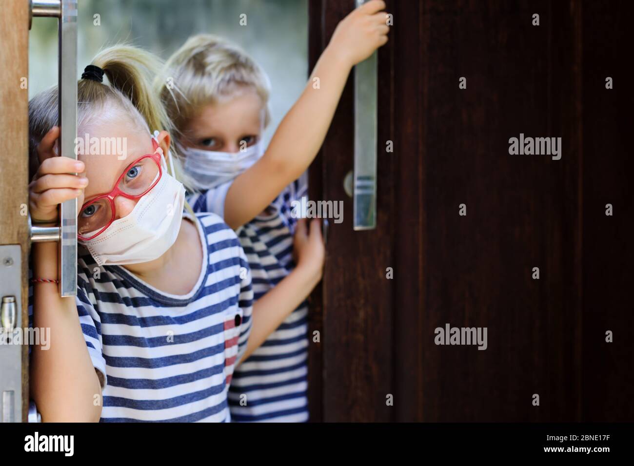 Les enfants ont l'air malheureux, déprimés après avoir séjourné à la maison en raison d'activités interdites dans la rue. Les enfants portant des masques médicaux sortent pour marcher dehors Banque D'Images