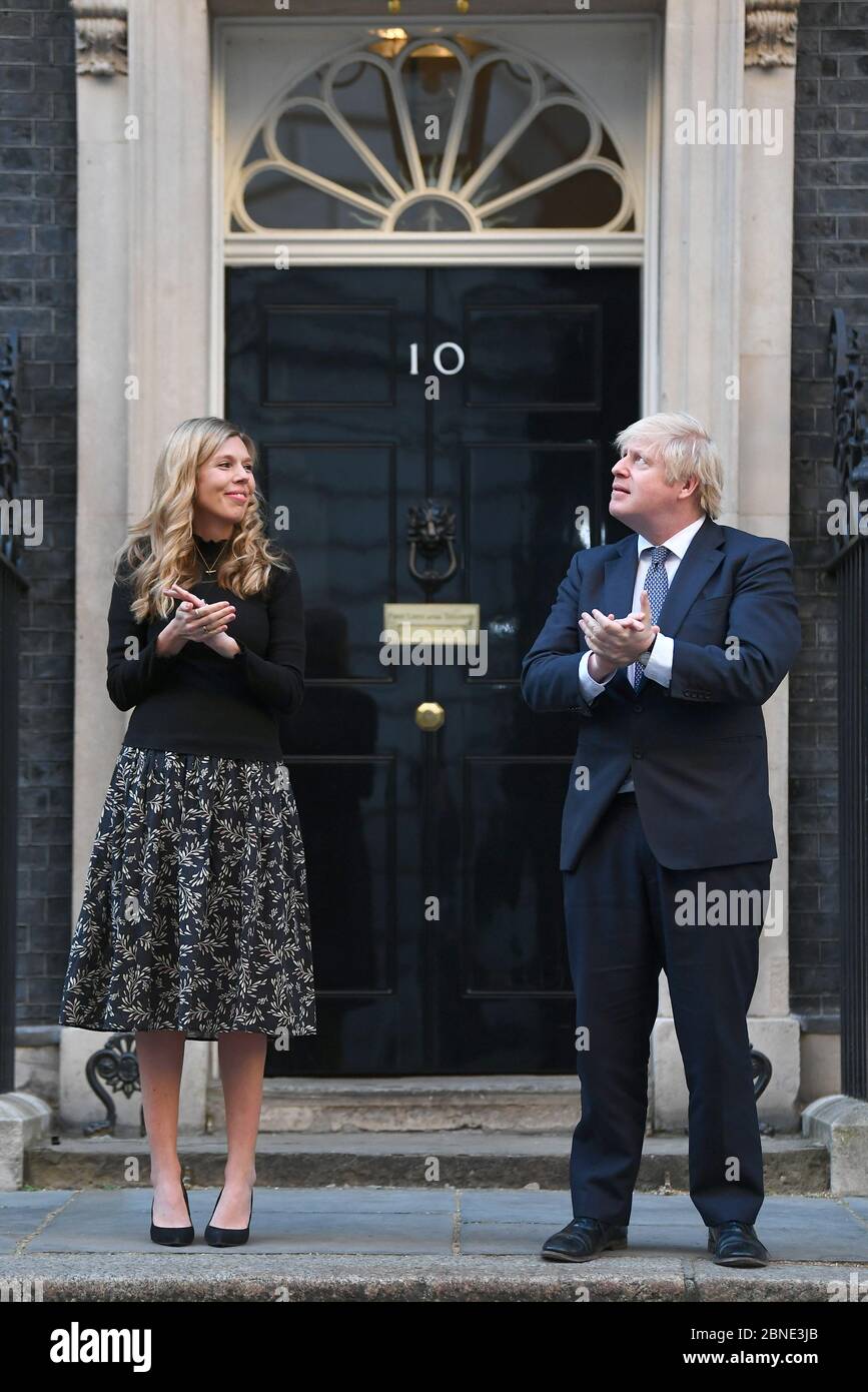 Le Premier ministre Boris Johnson et sa partenaire Carrie Symonds, se tiennent à Downing Street, Londres, pour se joindre aux applaudissements pour saluer les héros locaux lors du Clap national de jeudi pour que les soignants reconnaissent et soutiennent les travailleurs du NHS et les soignants qui luttent contre la pandémie du coronavirus. Banque D'Images
