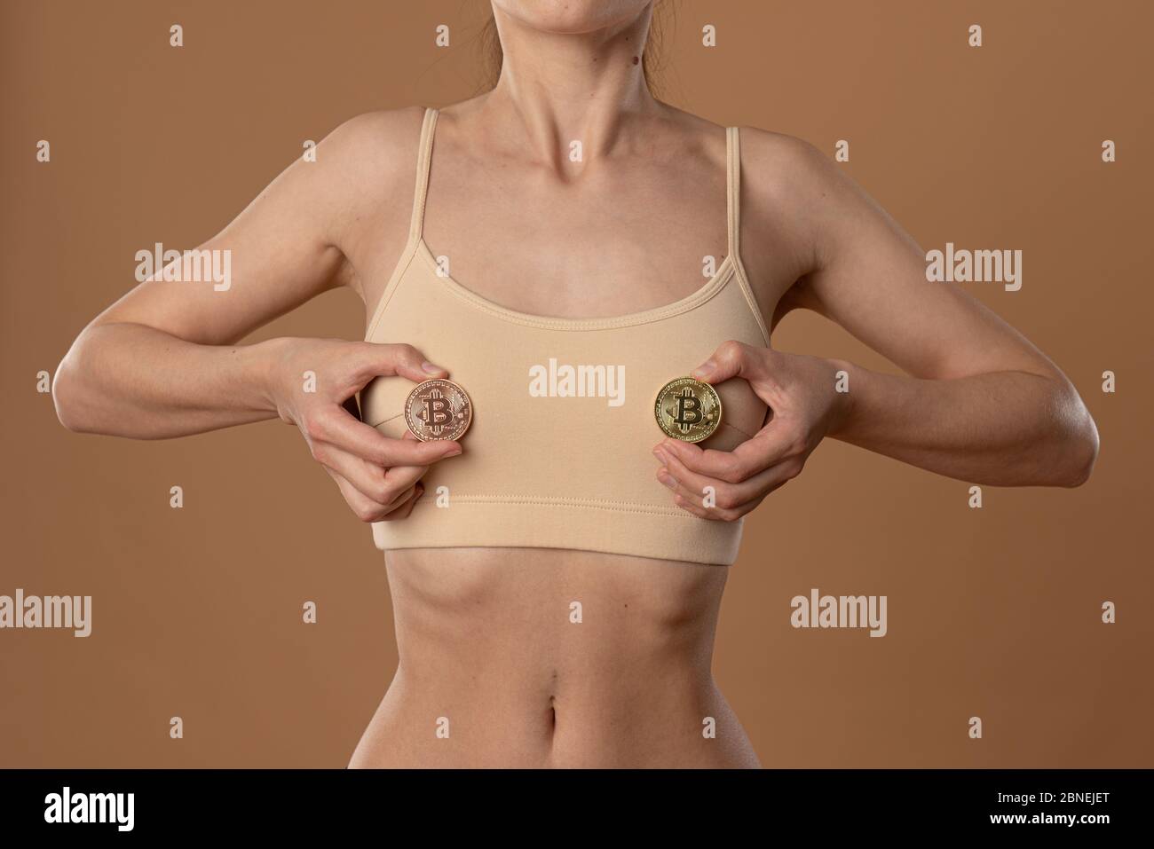 Photo courte d'une jeune fille mince en soutien-gorge beige qui tient le  timbet doré dans ses mains devant sa poitrine Photo Stock - Alamy