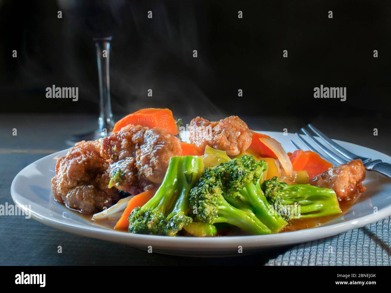 Poulet au brocoli dans une sauce aux huîtres, cuisine chinoise traditionnelle cantonaise avec carottes et une tasse de vin dans un fond noir, sauce asiatique Banque D'Images