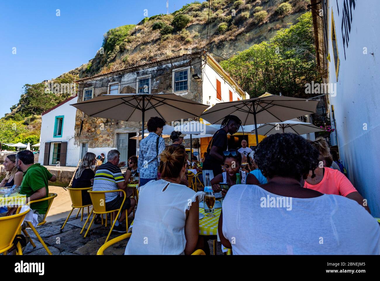 Les gens apprécient le beau temps d'été dans un restaurant en plein air près du Tage à Almada, Portugal Banque D'Images