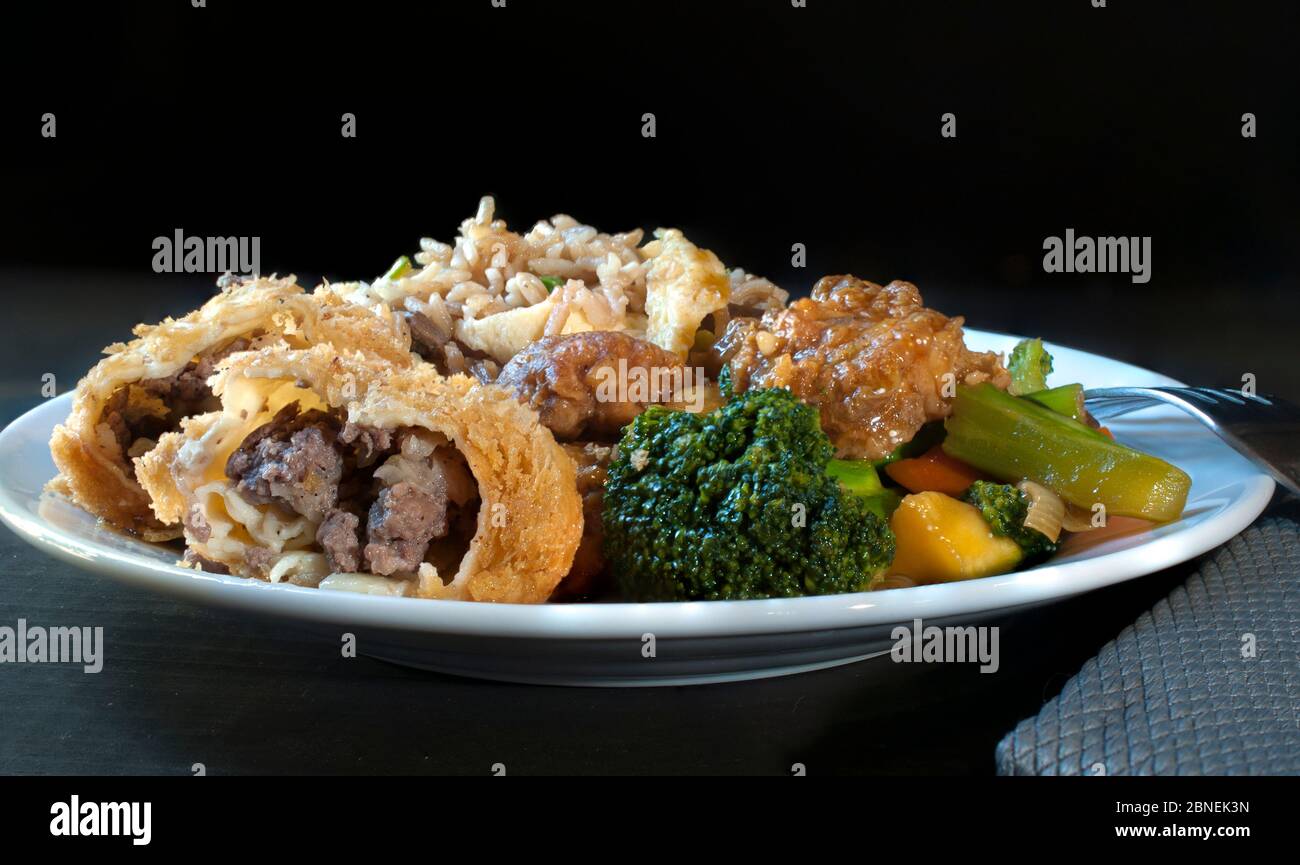 Poulet au brocoli, petits pains aux œufs et riz frit, cuisine chinoise cantonaise traditionnelle sur une assiette blanche sur fond noir Banque D'Images