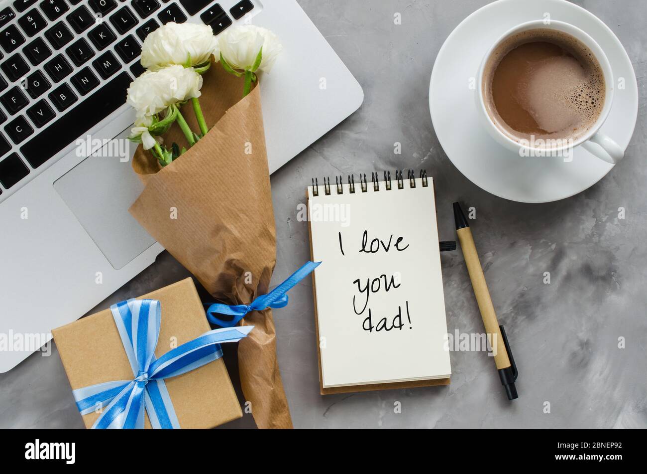 Carte de vœux avec inscription Je vous aime papa, ordinateur portable, boîte cadeau, café du matin et fleurs. Concept de fête ou d'anniversaire du père. Vue de dessus. Banque D'Images