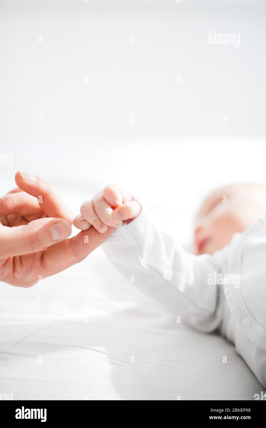 Bébé attrapant le doigt de la mère Banque D'Images