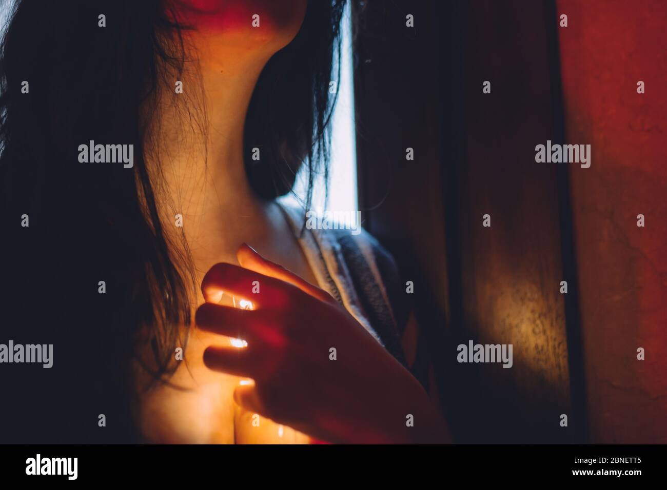 Femme avec une lumière qui brille vers le bas de sa gorge Banque D'Images