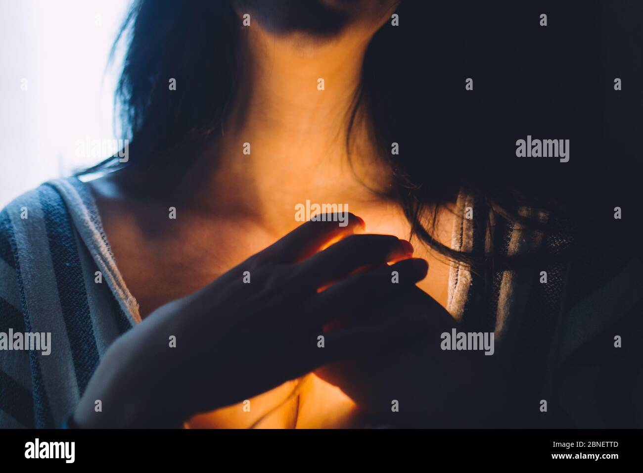 Femme stressée avec une lumière qui brille vers le bas de sa gorge. Banque D'Images