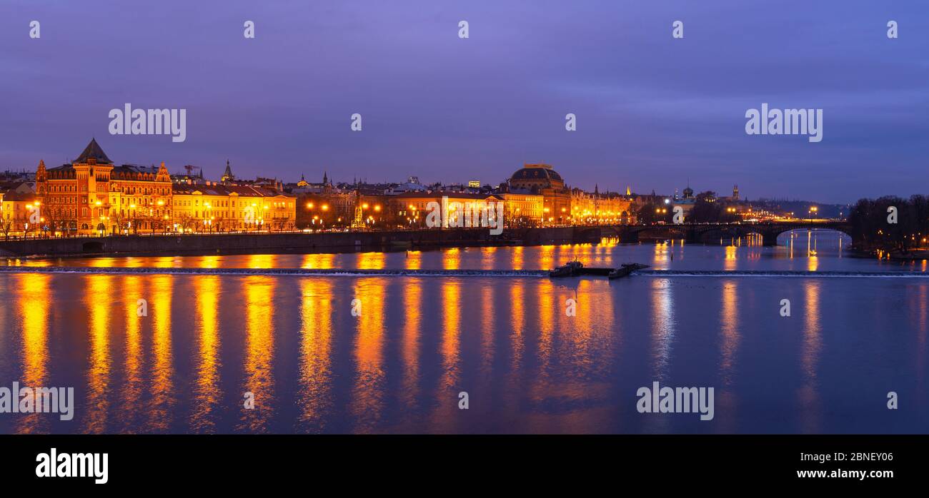 Panorama des façades de bâtiments historiques se reflétant dans la Vltava pendant l'heure bleue, Prague, République tchèque. Banque D'Images
