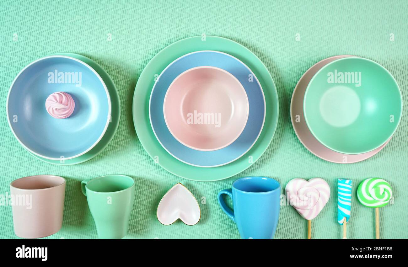 Vue de dessus de la moderne pastel rose, vert et bleu céramique vaisselle ensemble sur vert pâle. Concept créatif de cuisine, plan de cuisine avec négatif cop Banque D'Images
