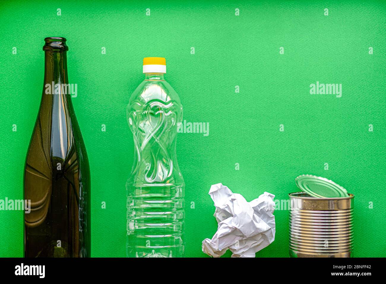 déchets, écologie, tri des déchets concept - disposition du tri des déchets en 4 types: verre, plastique, papier, métal sur un fond vert copie espace. Banque D'Images