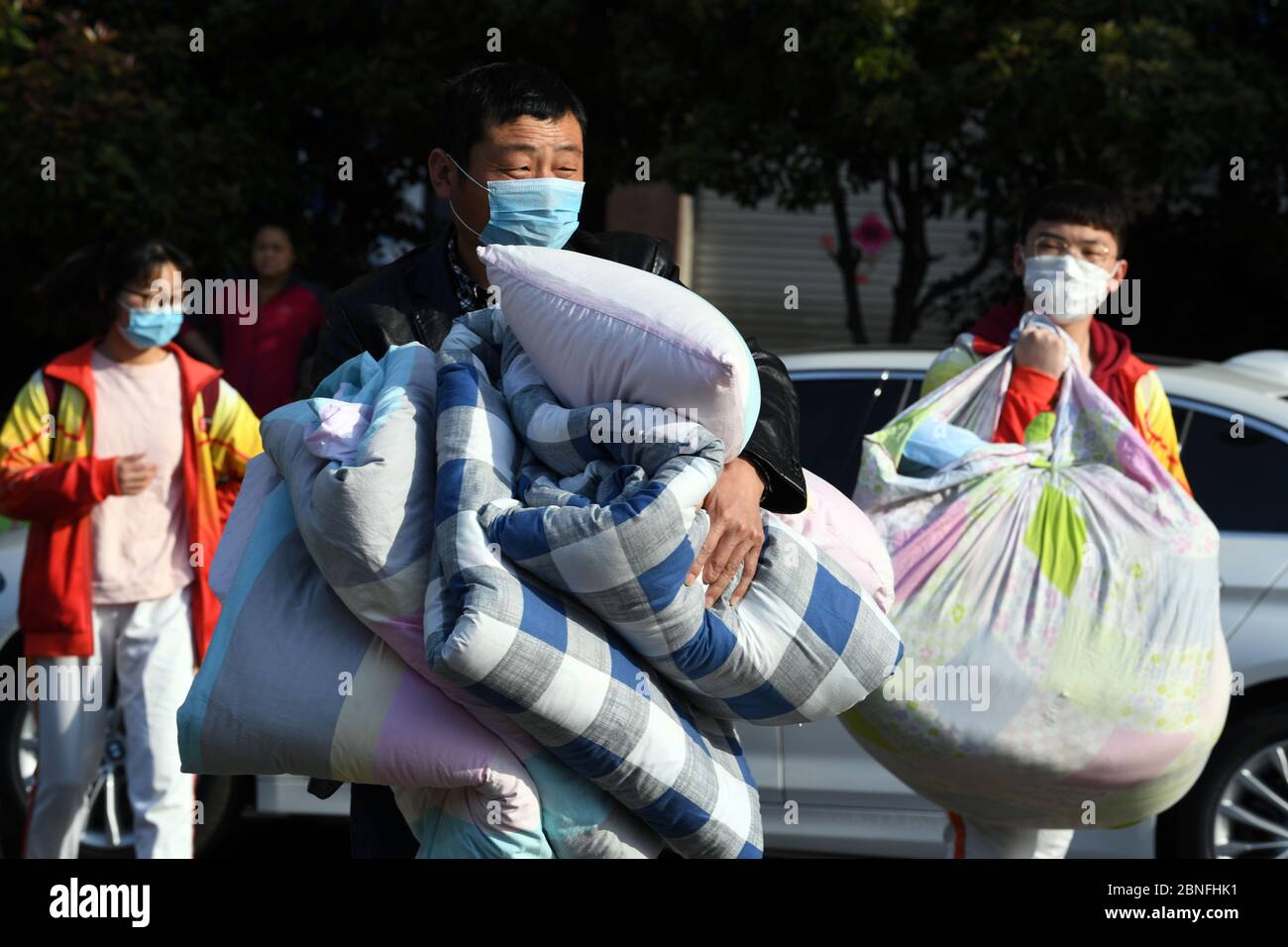 Les élèves avec masque facial retournent à l'école avec leurs bagages après deux vacances d'hiver et demie dans une école secondaire locale, la ville de Bozhou, en Chine orientale Banque D'Images