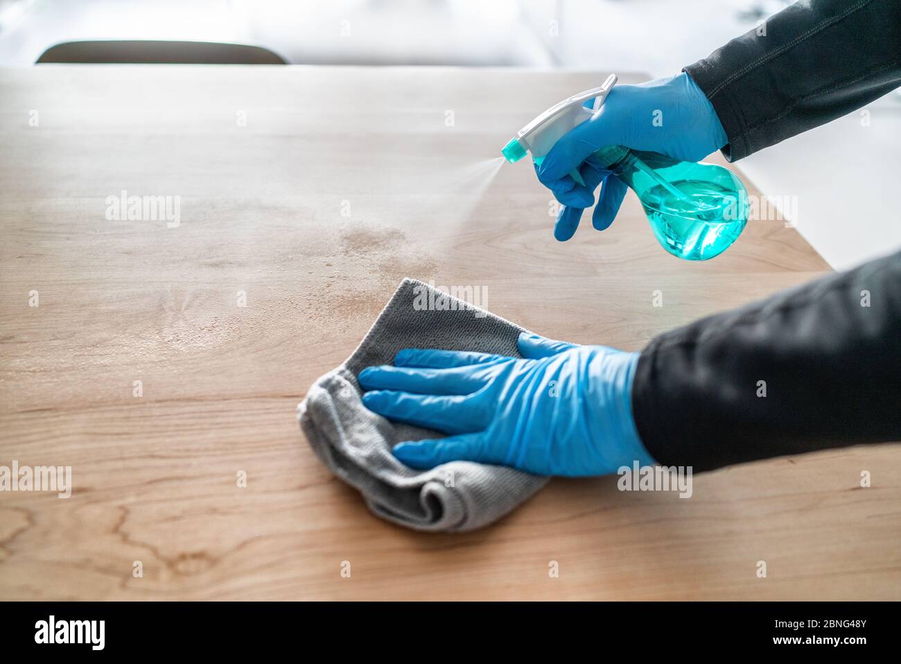 Nettoyage de surface pulvérisation liquide désinfectant antibactérien avec lavage en bouteille table à la maison . Homme utilisant des gants et une serviette pour le nettoyage du ressort. Banque D'Images