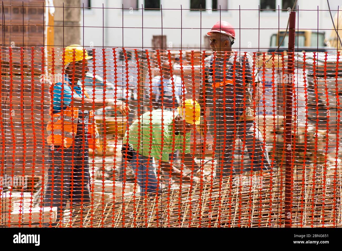 Les ouvriers de la construction équipés de casques de sécurité se tiennent derrière une clôture de protection Banque D'Images