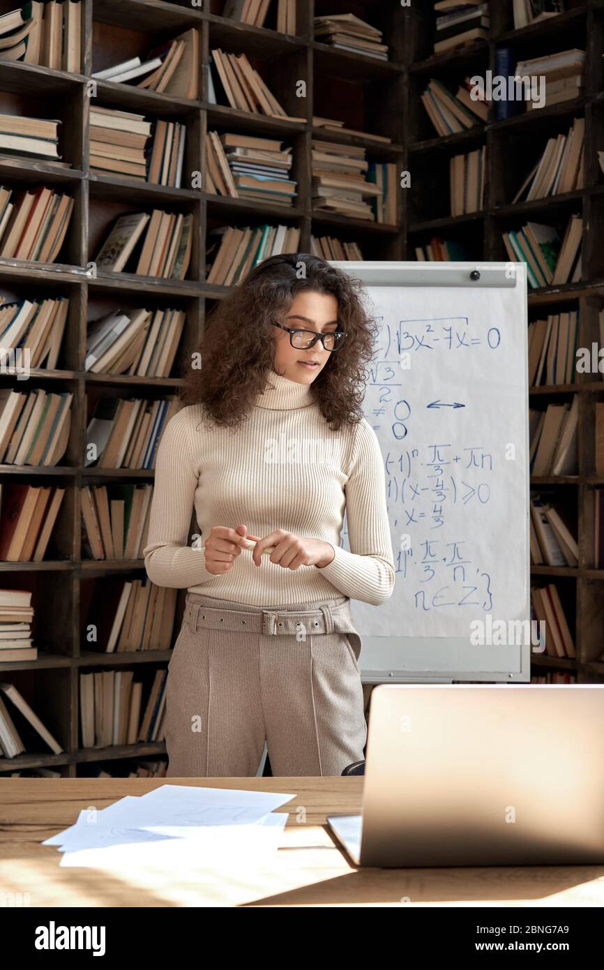 Femme hispanique enseignante travaillant en classe avec tableau blanc et ordinateur portable. Banque D'Images