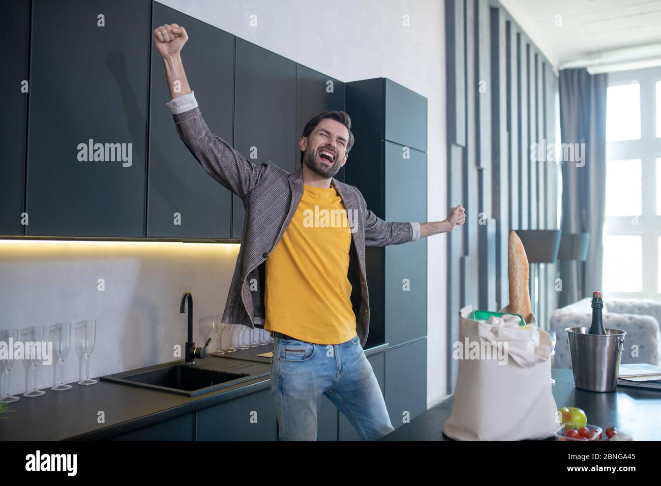 Homme gai aux yeux fermés se réjouissant dans la cuisine. Banque D'Images