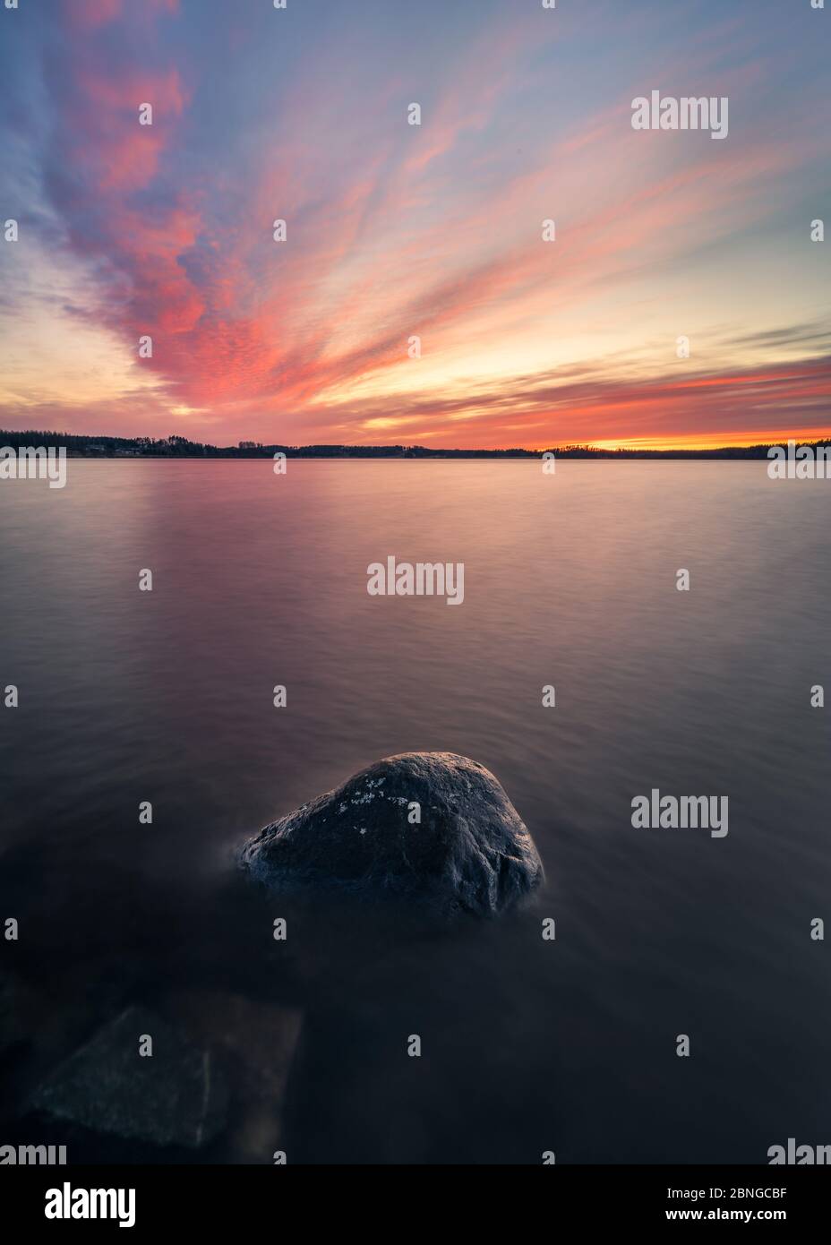 Coucher du soleil avec vue panoramique lac paisible et roche à la soirée de printemps en Finlande Banque D'Images Coucher du soleil avec vue panoramique lac paisible et roche à la soirée de printemps en Finlande Banque D'Images