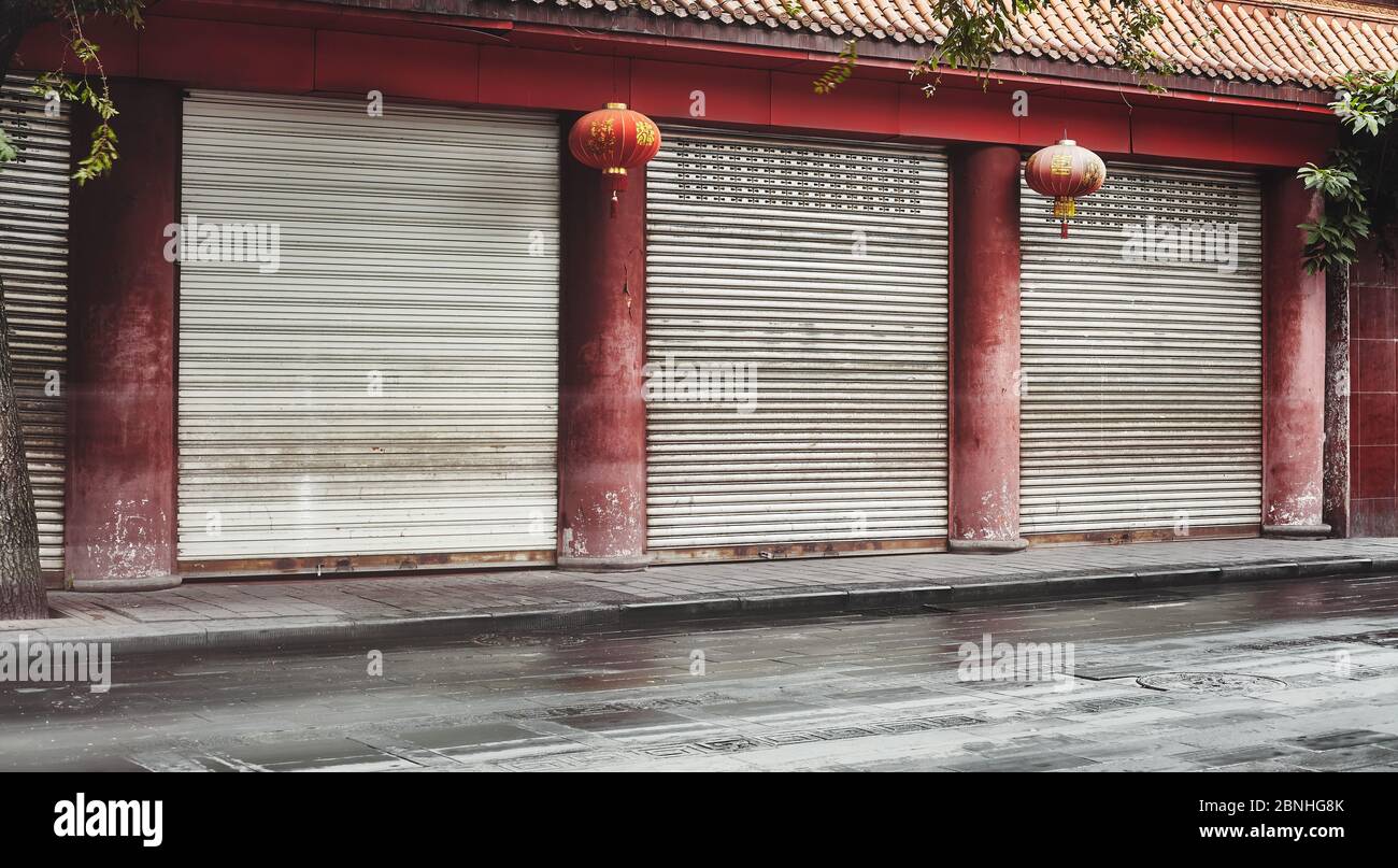 Rue vide et magasins fermés avec colonnes rouges et lanternes, couleurs appliquées, Chine. Banque D'Images