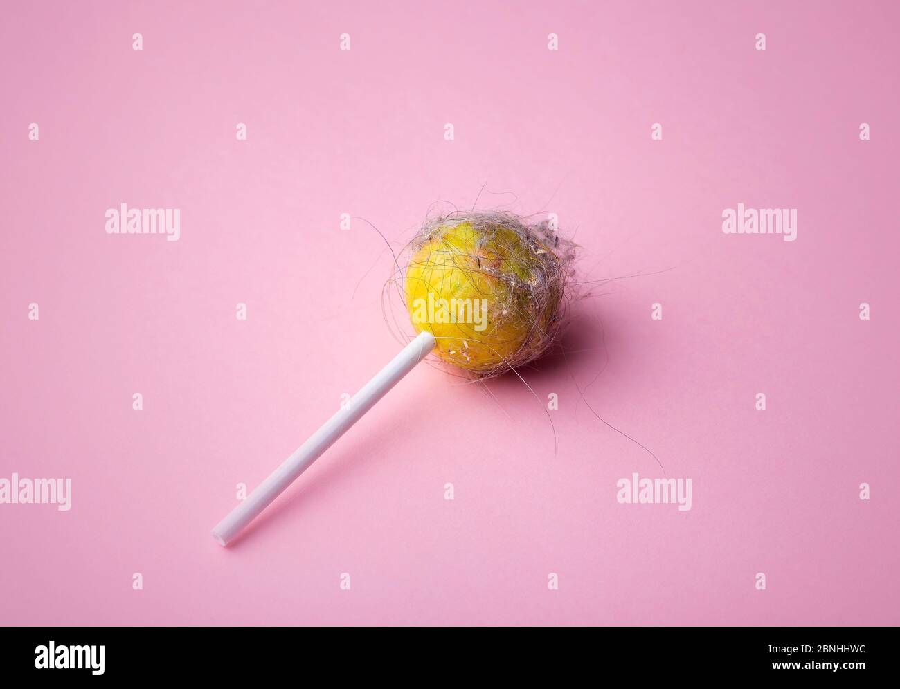 Un lollipop sale sur fond rose. Lollipop avec cheveux, poussière et saleté  sur un fond vide minimal. Concept artistique minimal Photo Stock - Alamy