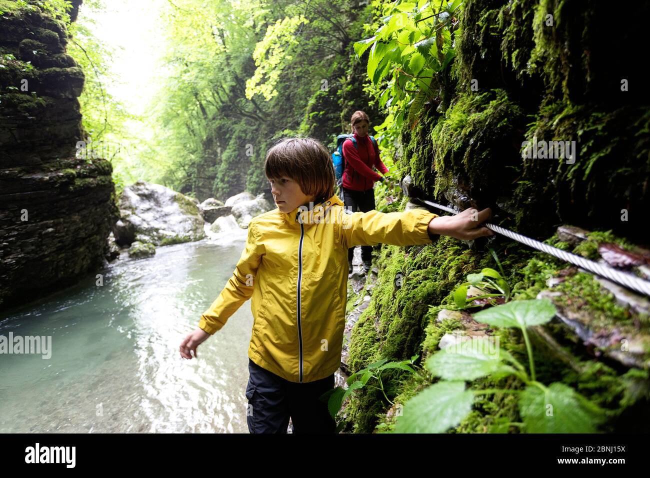 Mère et fils marchant dans les gorges de la rivière tenant la corde de sécurité à la cascade de Kozjak, Slovénie Banque D'Images