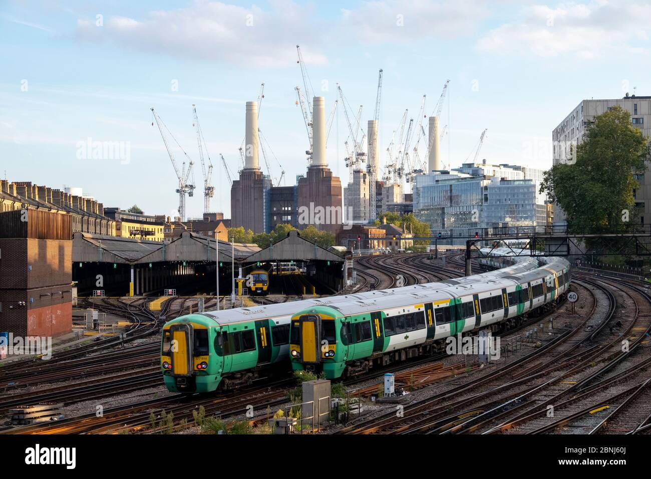Trains de voyageurs en direction de la gare Victoria de Londres avec la centrale électrique Battersea en construction, Londres, Angleterre, Royaume-Uni, Europe Banque D'Images