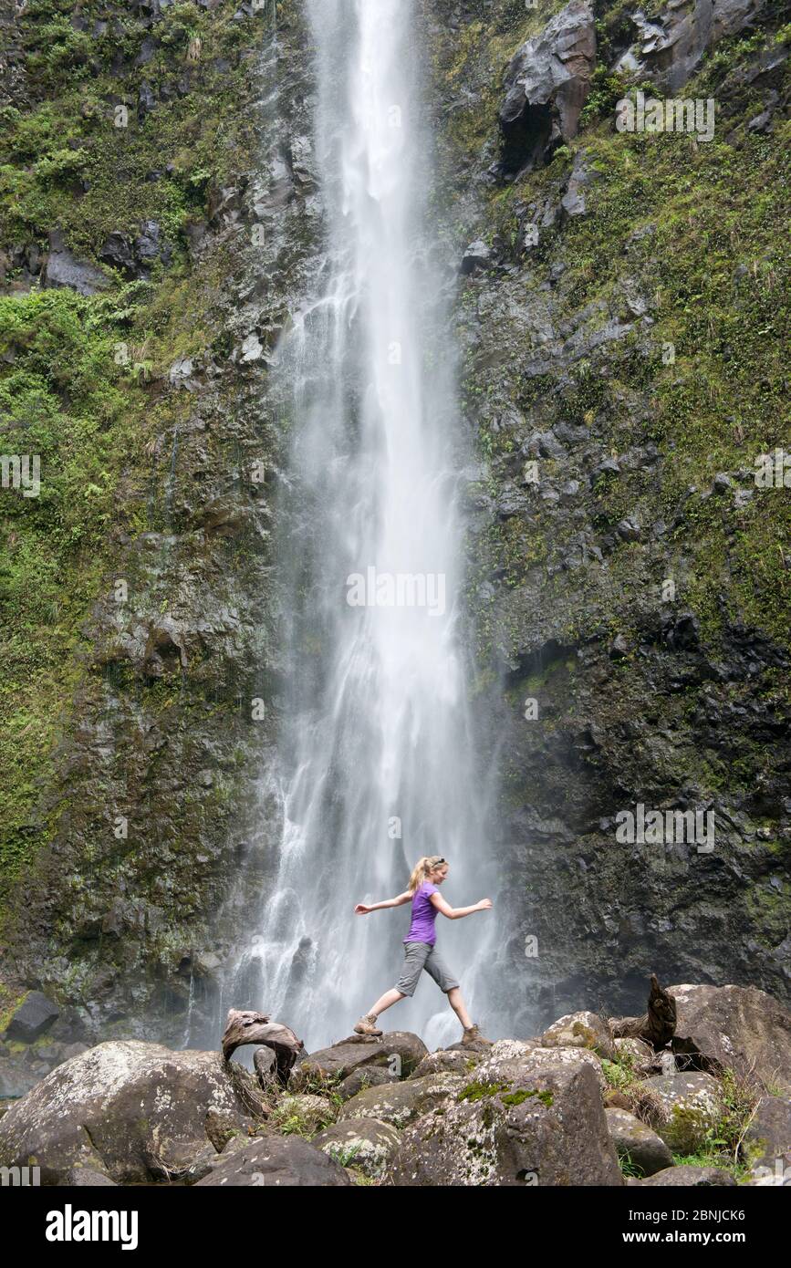 Randonneur bondissant devant une cascade le long du célèbre sentier de Kalalau, le long de la côte Na Pali de Kauai, Kauai, Hawaii, États-Unis d'Amérique, Amérique du Nord Banque D'Images