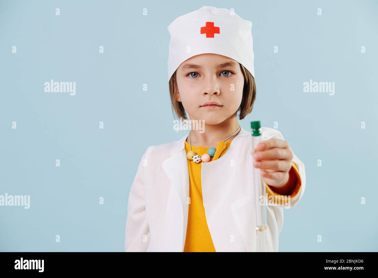 Fille sérieuse dans un peignoir blanc tenant flacon dans une main, regardant de manière inquiétante la caméra. Banque D'Images