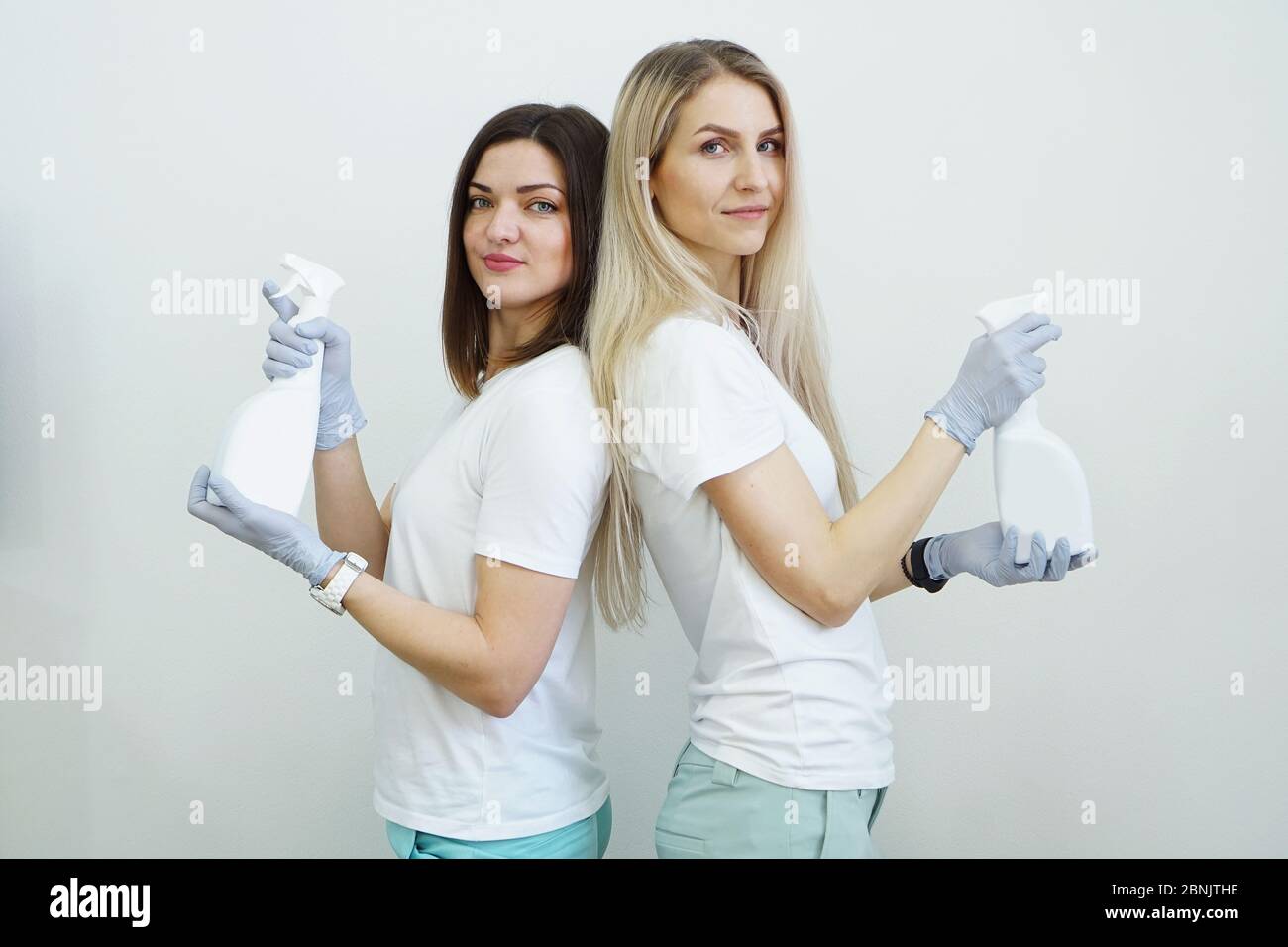 Deux femmes tiennent une bouteille vaporisée avec un antiseptique ou un détergent comme des pistolets. Concept de santé ou de nettoyage Covid-2019 Banque D'Images
