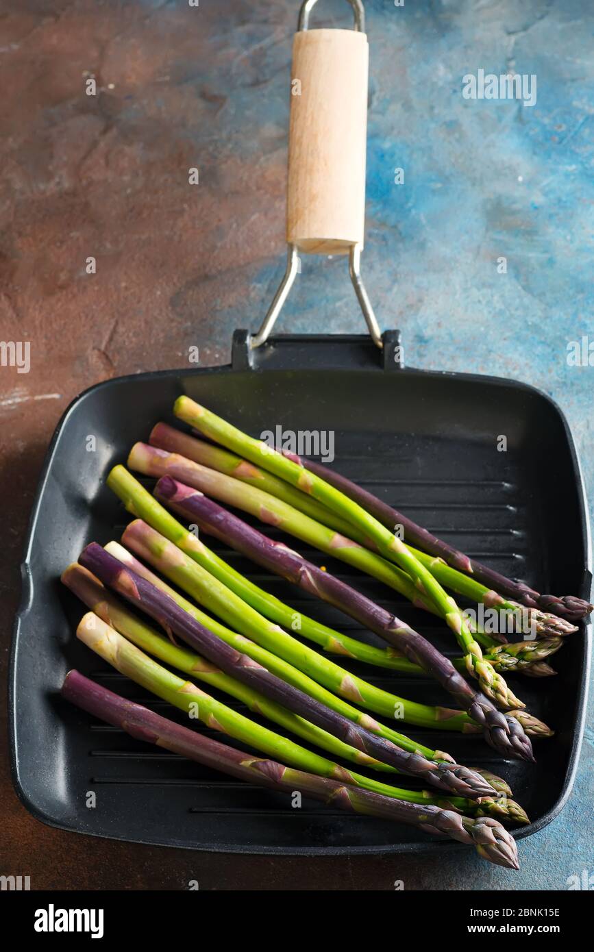 Pile d'asperges naturelles fraîchement cueillies dans une casserole prête à cuire des plats végétariens sur un fond de pierre sombre. Banque D'Images