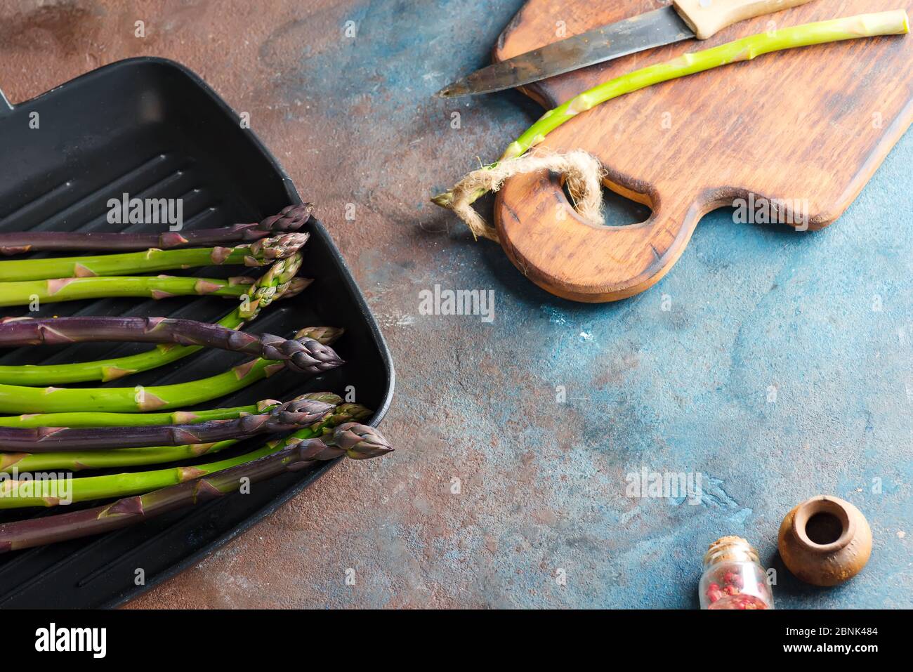 Légumes d'asperges verts et violets naturels frais dans une casserole prête à cuire des aliments sains sur fond de pierre. Banque D'Images