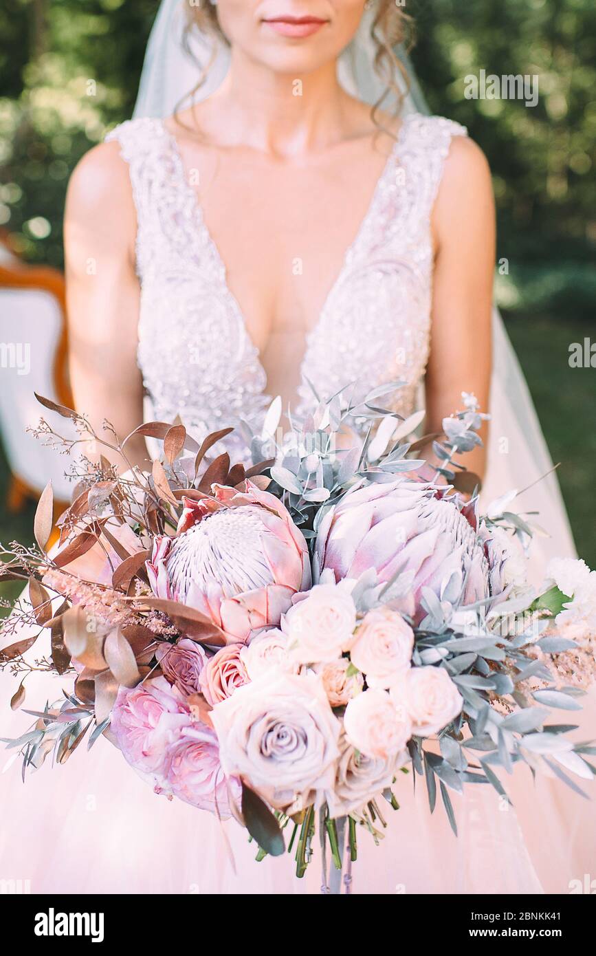 Gros plan du bouquet de roses, d’œillets, de prothés et de feuilles d’argent d’une mariée dans des tons de blanc, rose, violet et lavande. La mariée tient un bouquet en lui Banque D'Images