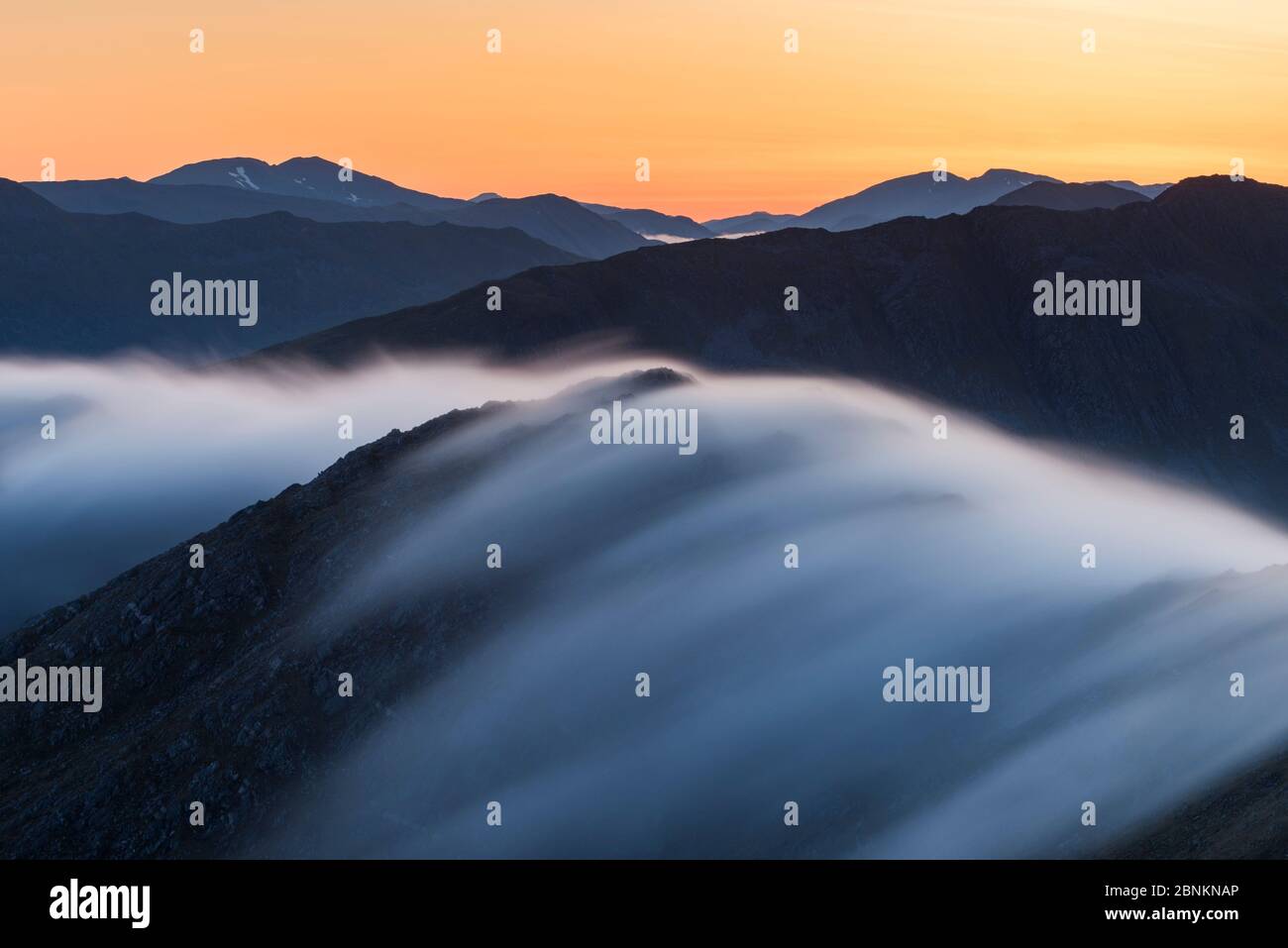 Une longue exposition de brume circulant sur Bhudhie Bheinn à l'aube avec les montagnes de Kintail sur l'horizon. Knoydart, Écosse, Royaume-Uni, juin 2016. Banque D'Images