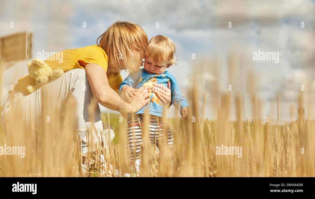 Printemps Portrait d'un adorable petit garçon avec jouet ours dans un champ parmi les oreilles sèches et l'herbe, la pyramide de foin et la paille . En plein air. Joyeux été et Banque D'Images