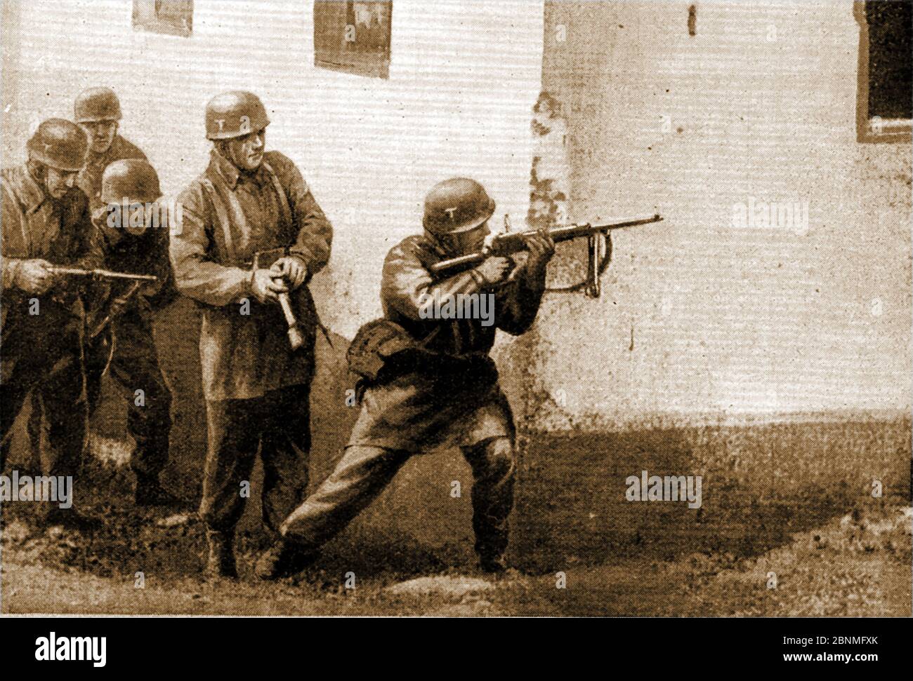 Deuxième Guerre mondiale - bataille de la Grèce alias opération Marita ou Unternehmen Marita - UNE image imprimée de 1941 montrant les parachutistes allemands nazis en action à Corinthe, Grèce. Un soldat tire au coin d'un bâtiment tandis que l'homme derrière se prépare avec une grenade à main.opération Marita a suivi l'invasion italienne en octobre 1940. Elle est parfois connue sous le nom de guerre gréco-italienne. Banque D'Images