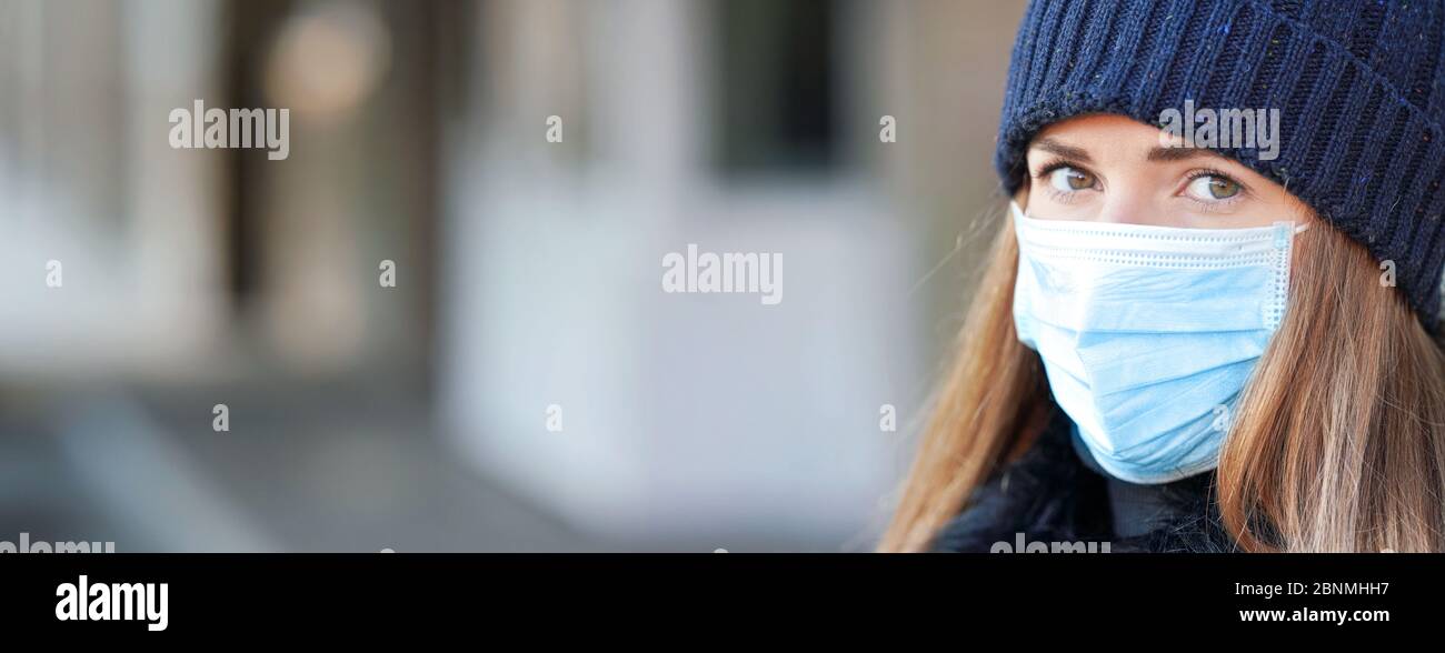 Jeune femme portant un virus bleu jetable visage bouche masque de nez, gros plan portrait - large bannière avec espace pour le texte côté gauche. Coronavirus covid-19 Banque D'Images
