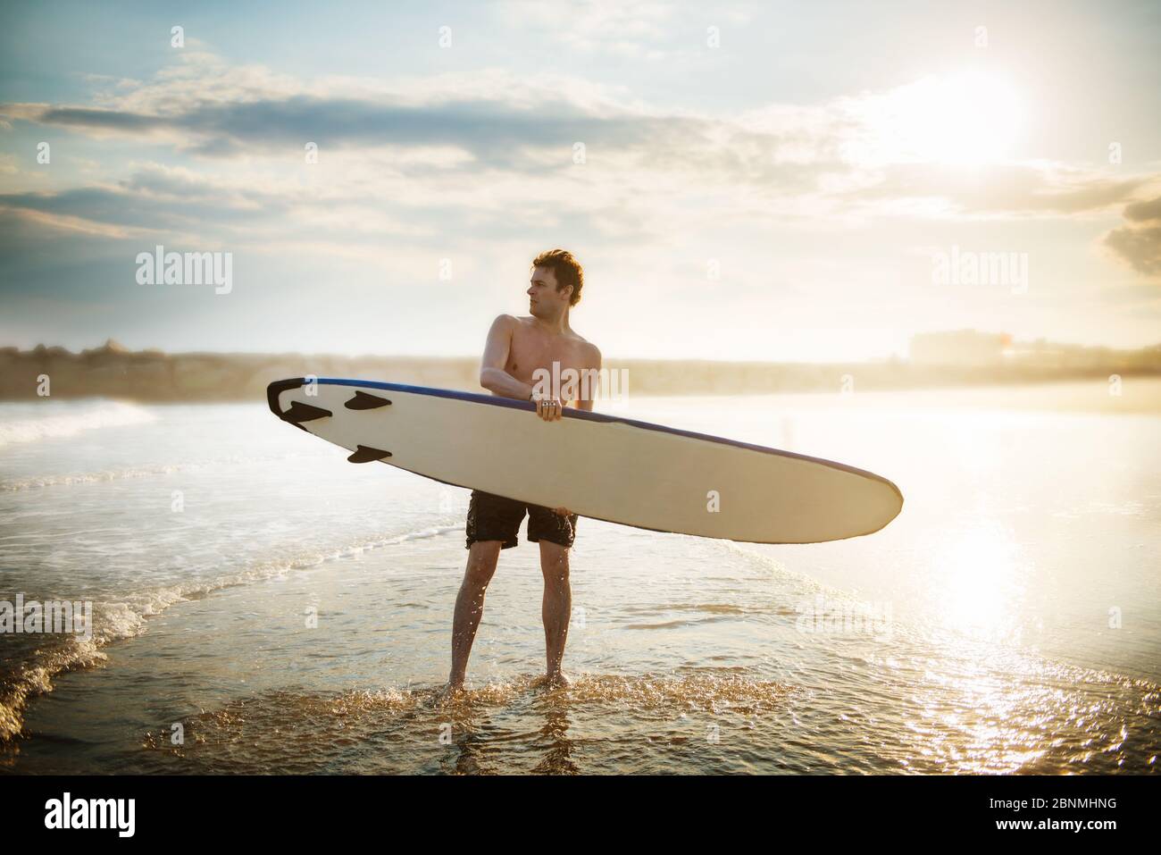 Jeune homme marchant sur la plage avec un surf Banque D'Images