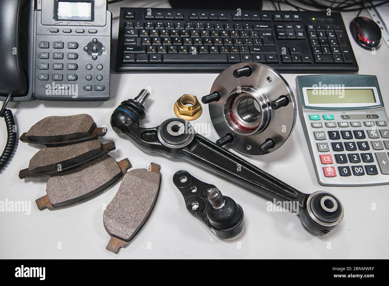 pièces de voiture disposées sur une table avec un téléphone, une calculatrice et un clavier d'ordinateur à faible profondeur de champ Banque D'Images